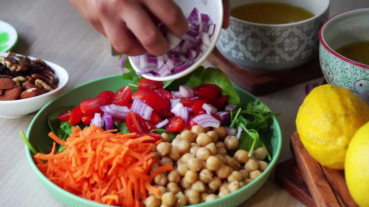 Making a salad adding onions to plate with spinach and carrots chick peas cilantro dressing lemon