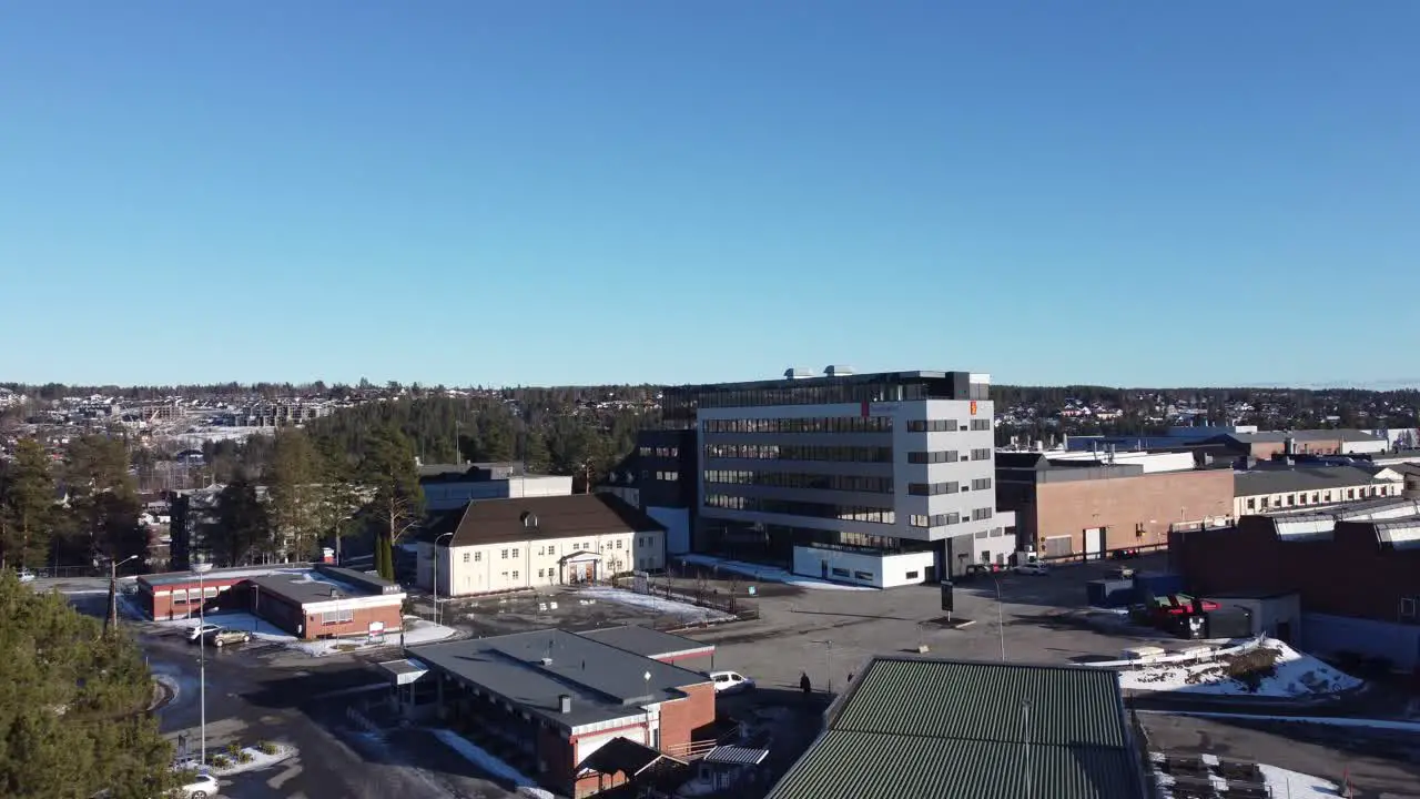 Kongsberg Defence and Aerospace headquarter in Norway Manufacturer of missiles and advanced military weapon systems Ascending aerial watching huge office building with logo at sunny winter day