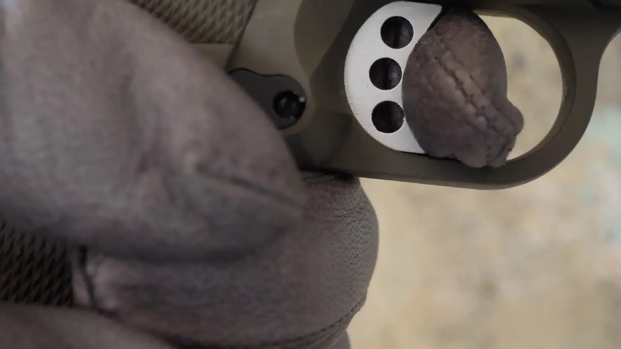 Close-up of a gloved hand pulling the trigger of a gun