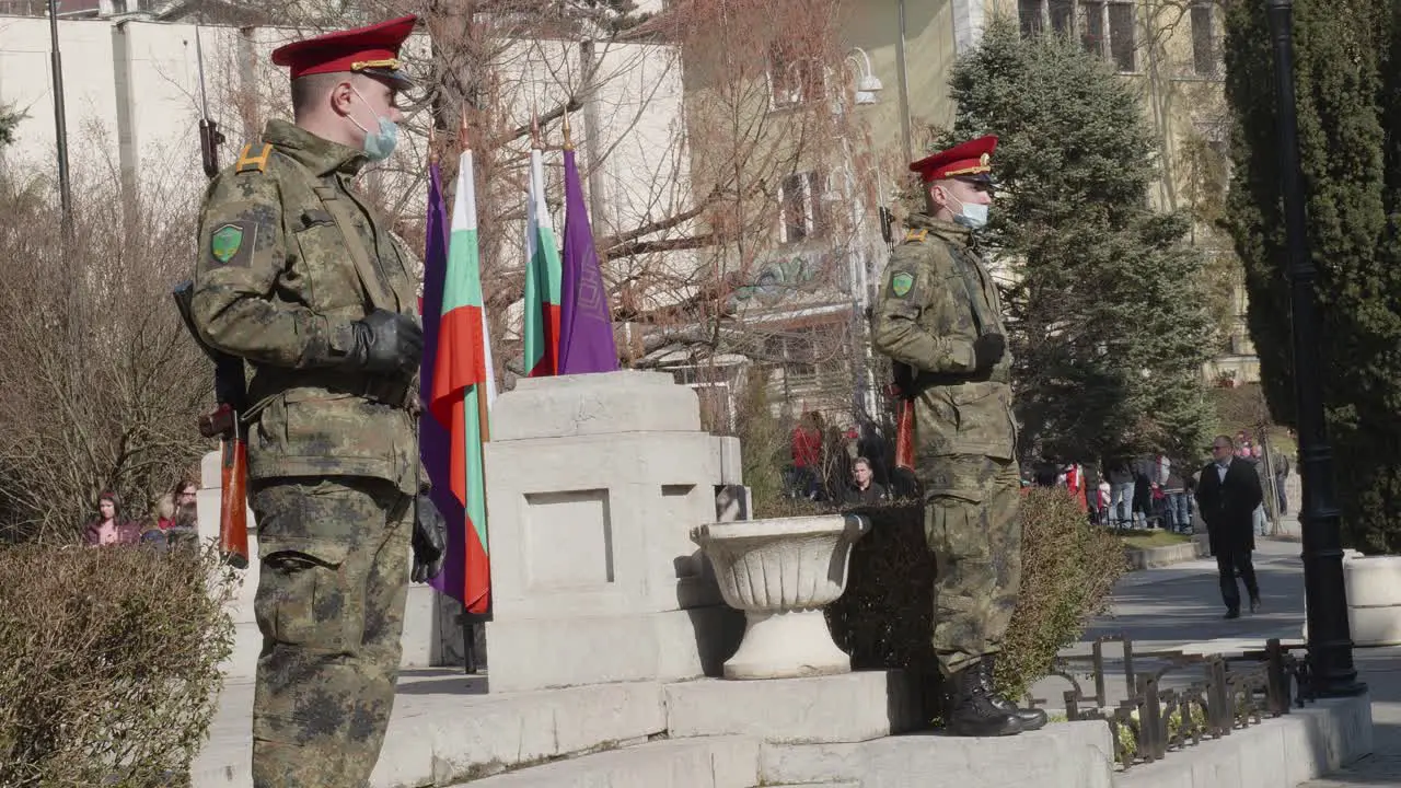 Two soldiers with weapons in camouflage uniform wearing anti covid masks at memorial parade service on Bulgaria Independence day