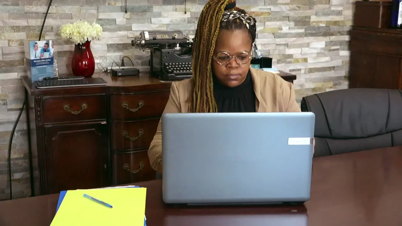 Black business owner wearing glasses working on computer in conference room