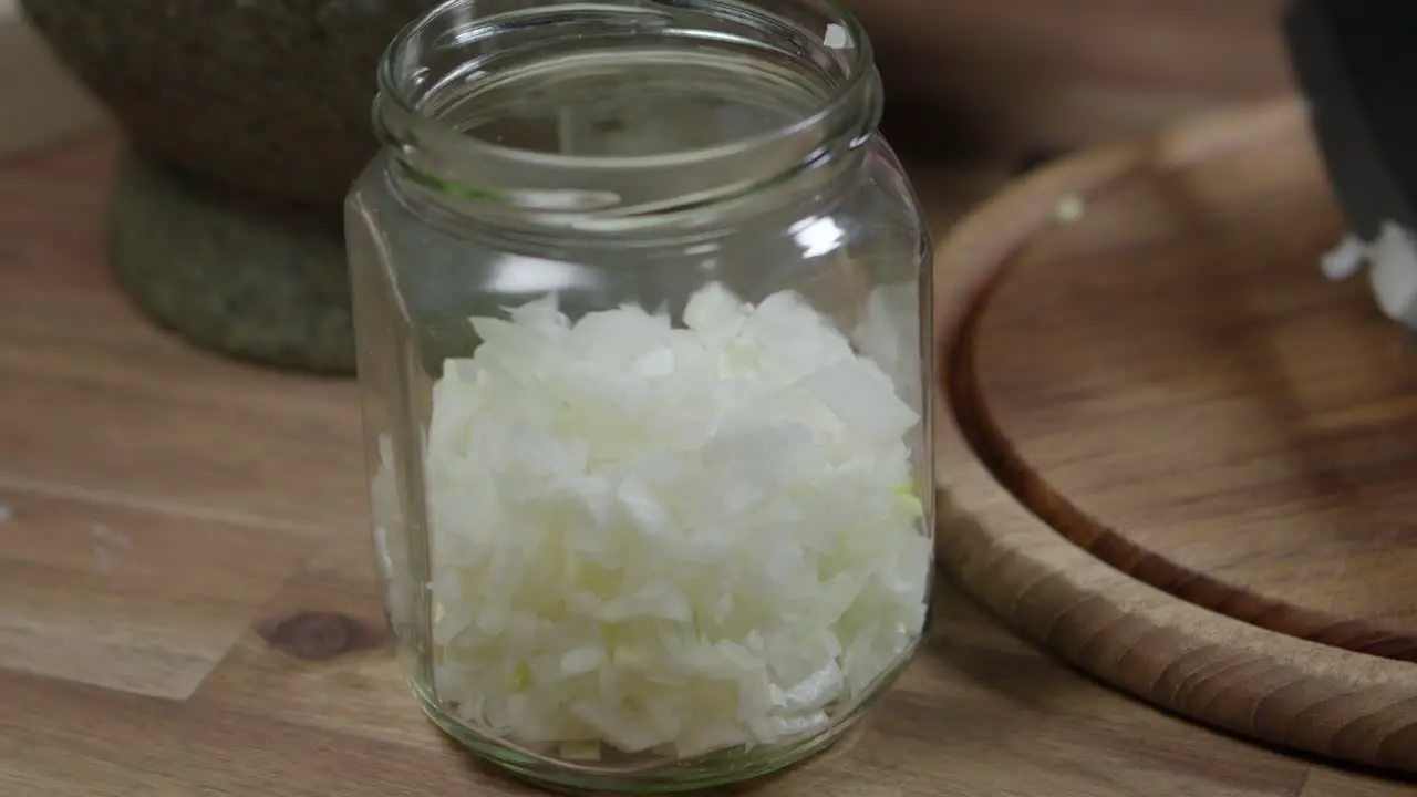 Adding chopped onion to a glass jar close up