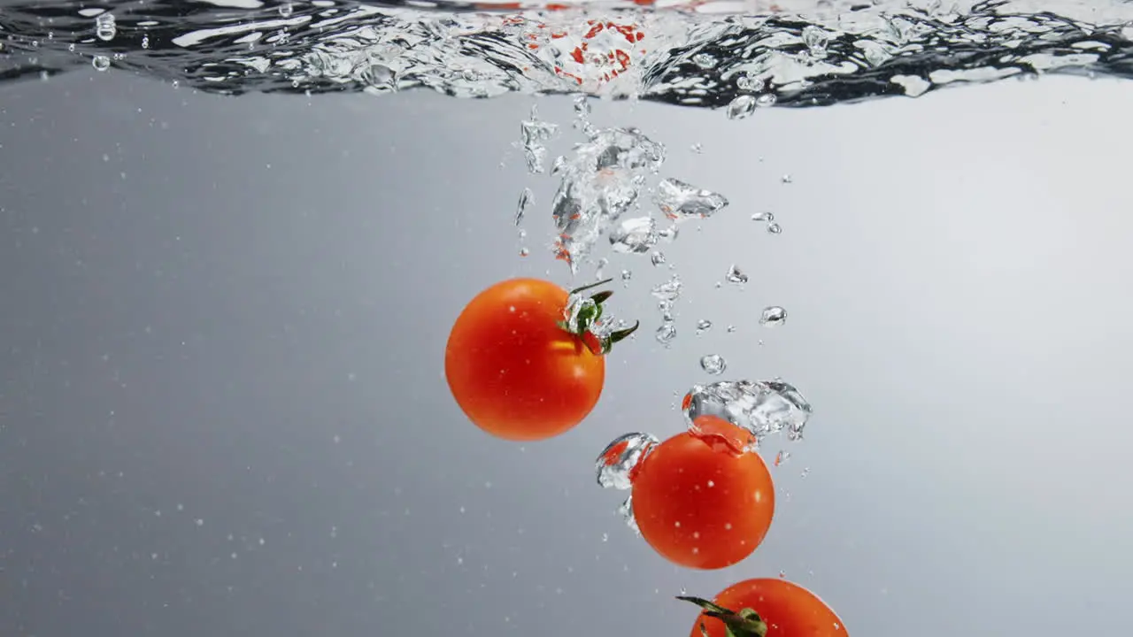 Tomatoes falling into boiling clear water