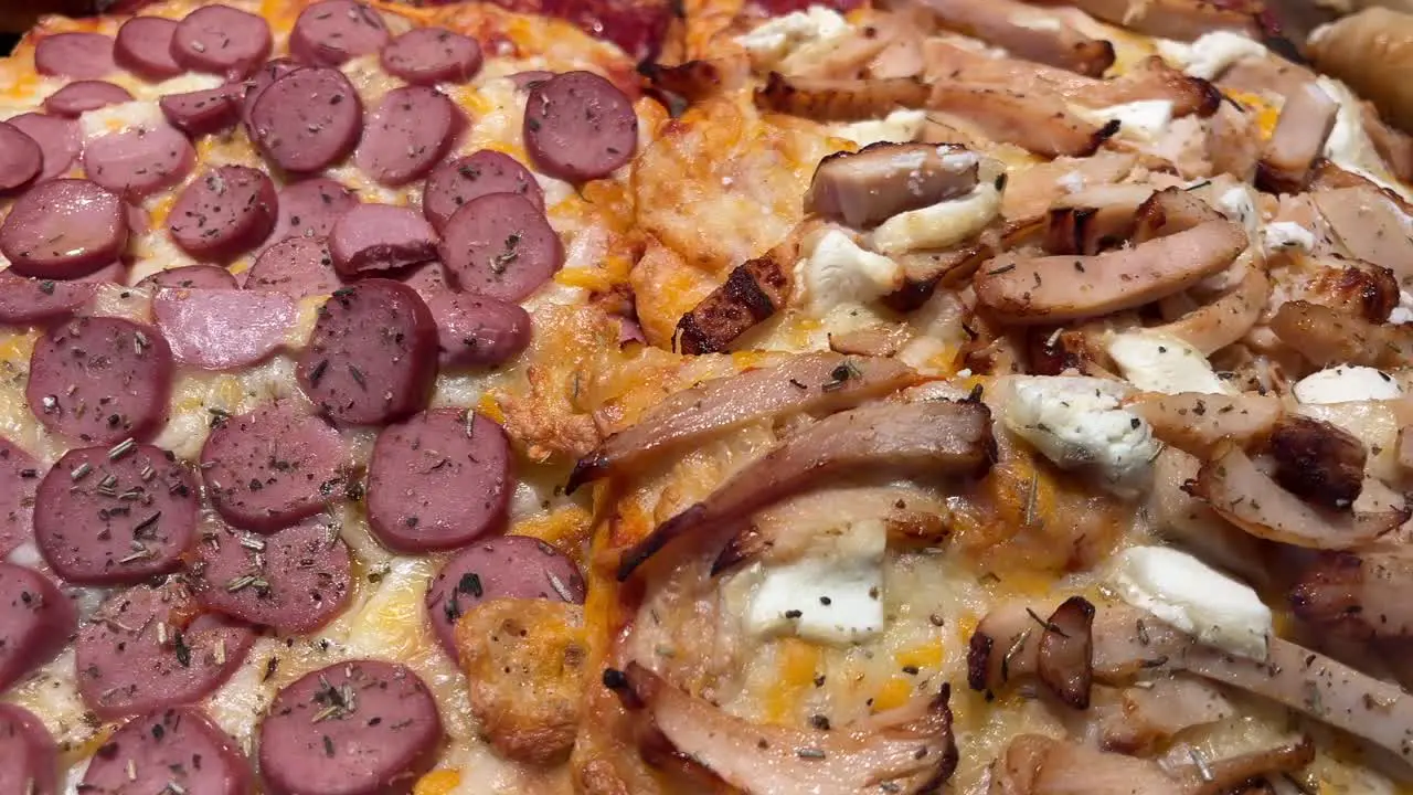 Close-up of sliced pizza with meat toppings on a wooden surface