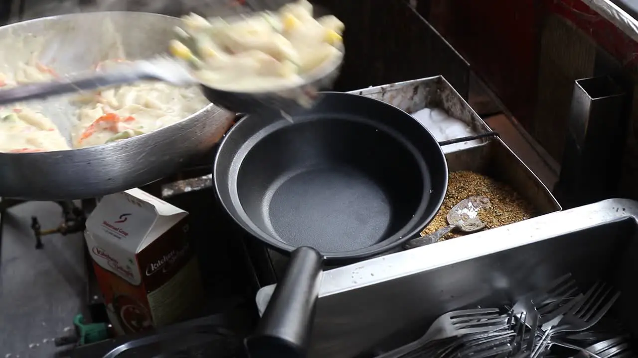 Professional chef pours white sauce Pasta into a pasta pan at a street food shop at Chat Gali in Agra India on 07 March 2021