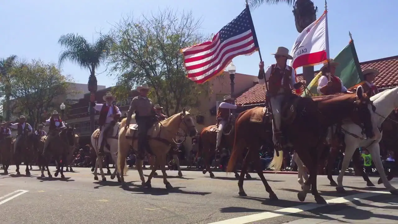 Cowboys on horseback ride through a small town during a 4th of July parade