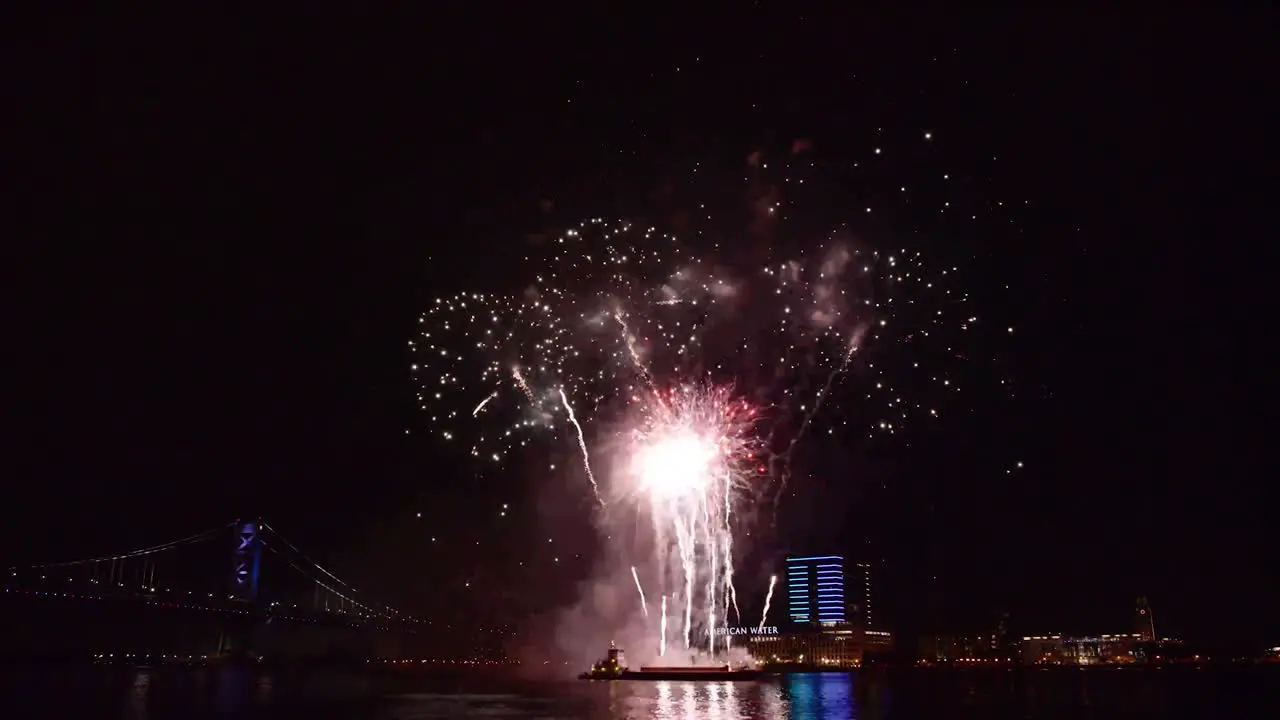 A Fireworks Display Takes Place Over the Water By A Bridge In America