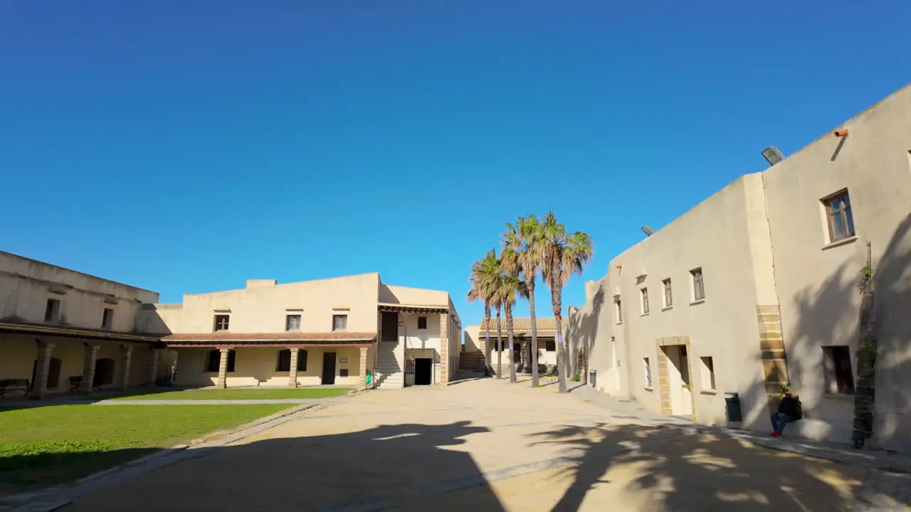 Framed by two towering cannons this view captures the historic architecture of a courtyard in Cádiz complete with palm trees and clear blue skies