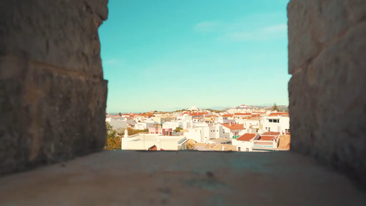 Portugal Loule city through castle wall battlements under blue sky with pull-in camera movement 4K