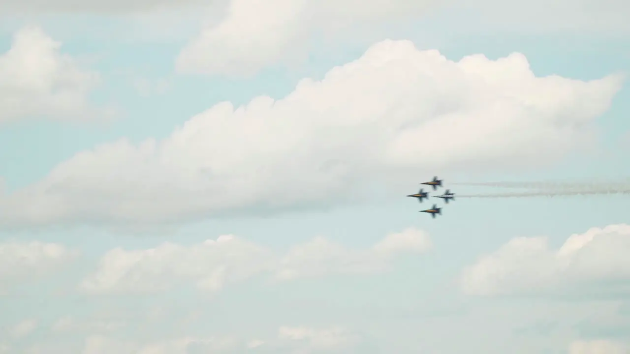 Military jets flying in formation enter a still frame and fly at speed from right to left leaving contrails in their wake