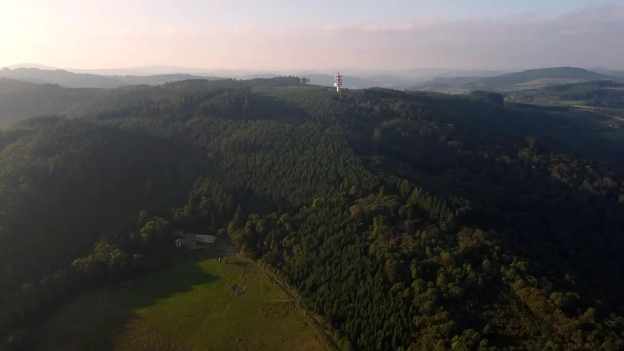 Aerial view of 5G tower base telecom station in a remote area on the top of the hill in wild evergreen forest tree during sunset