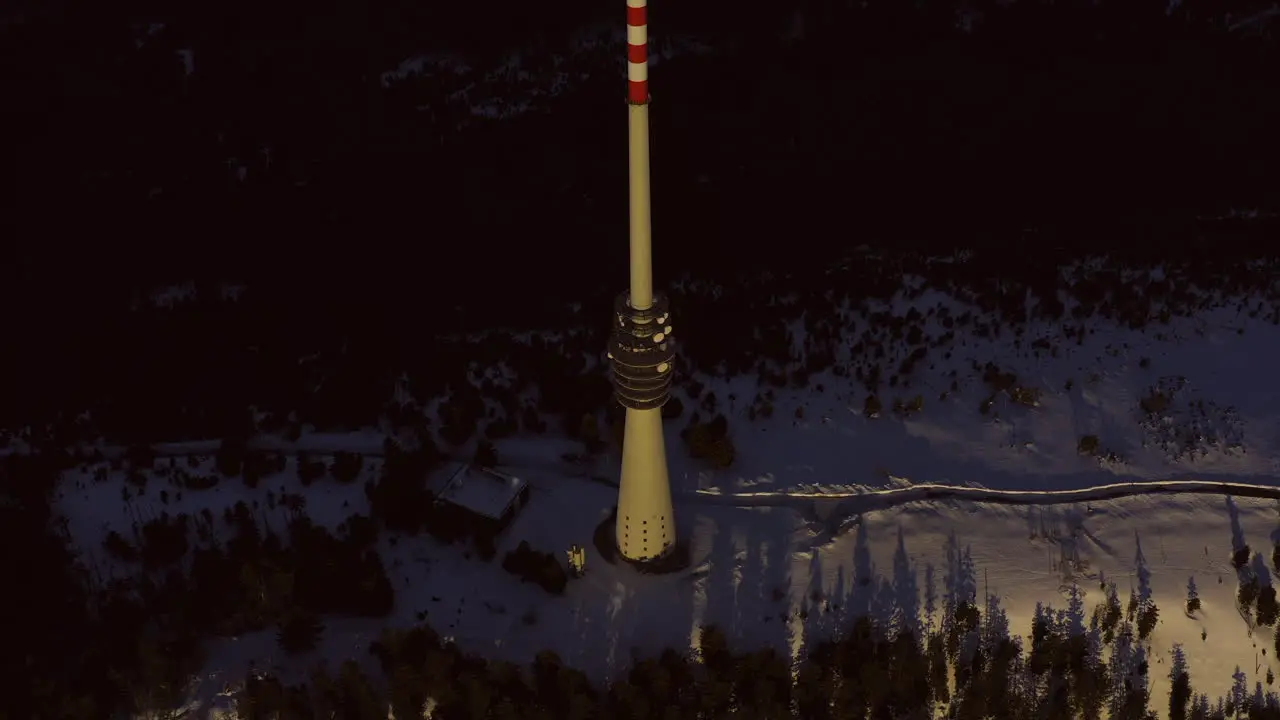 Aerial tracking shot of big broadcast tower at sunset on the snowy mountain Hornisgrinde in the black forest