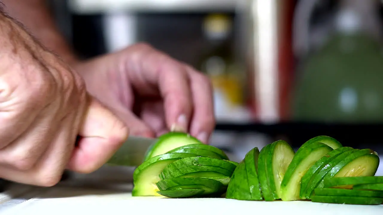 Close shot of a zucchini being chopped on a white table