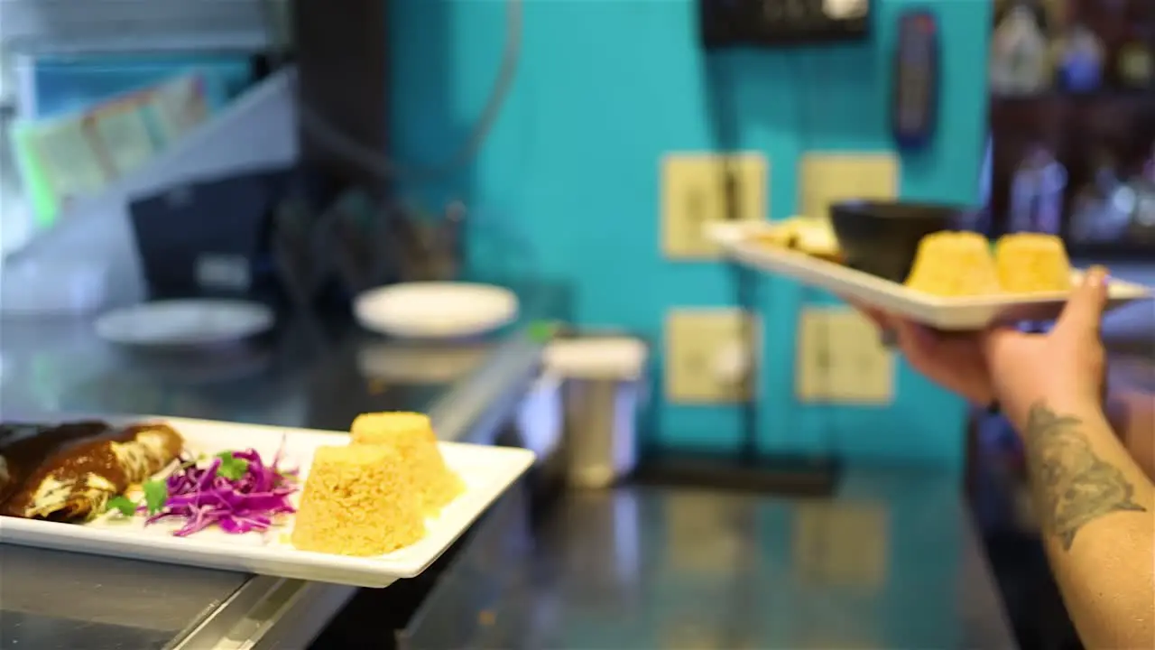 dynamic shot of a server grabbing homemade style Mexican food to serve to guest at a local restaurant