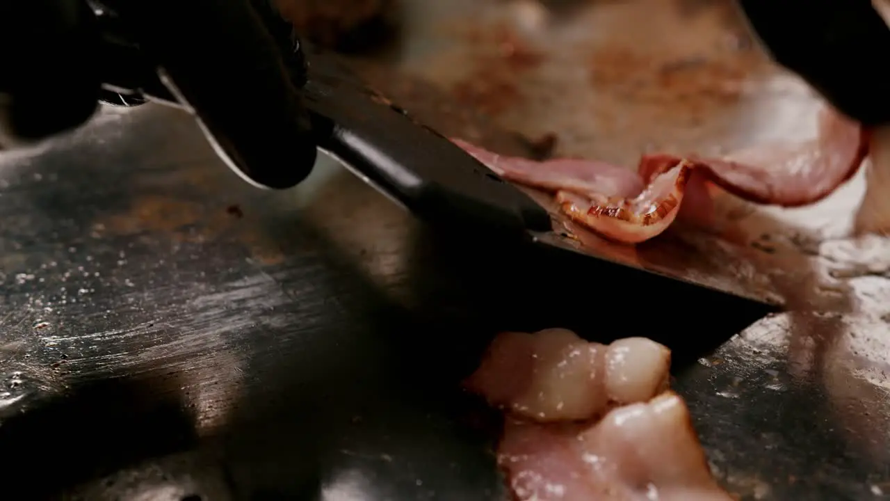  Frying delicious bacon strips in slow motion on a metal plate