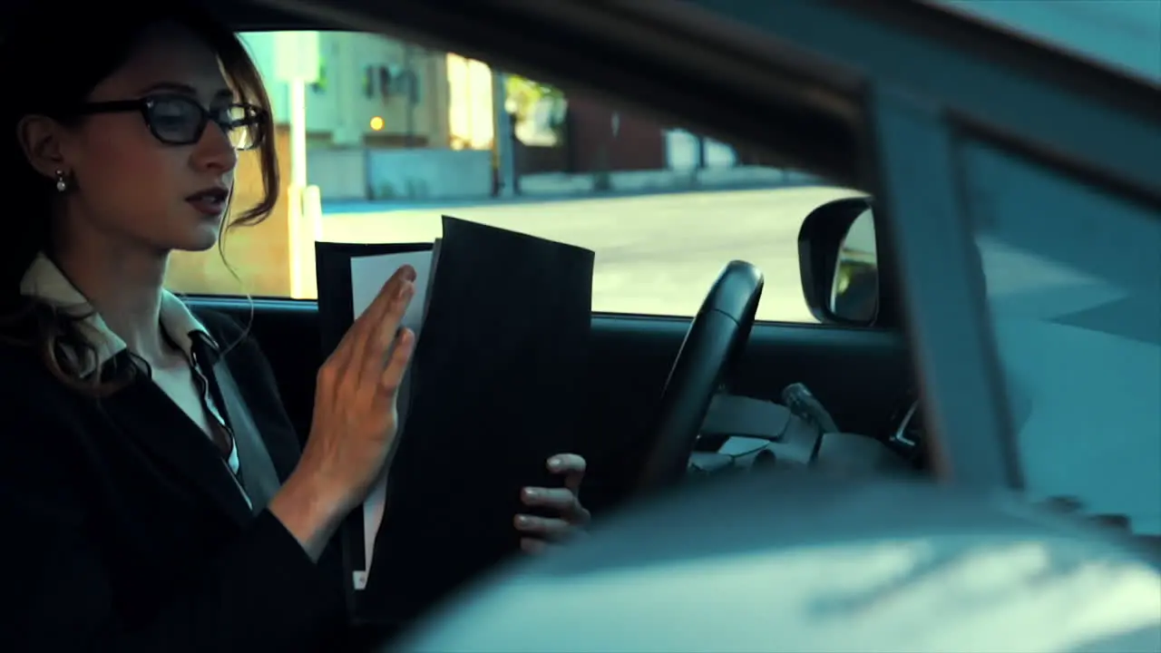 Attractive caucasian business woman in a parked car going over paperwork rifling through her documents in her portfolio