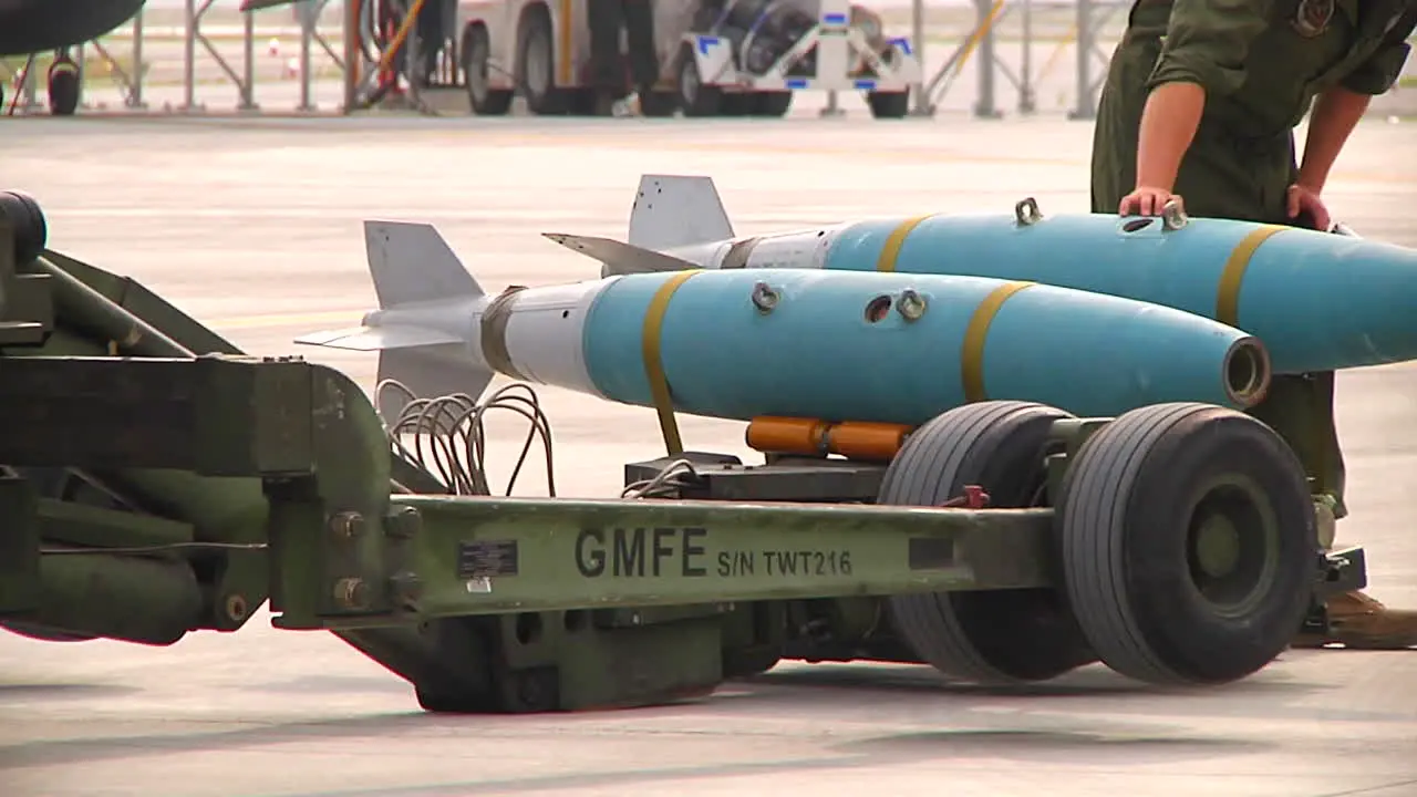 Bombs Are Loaded Onto A Jet Aircraft By Military Personnel