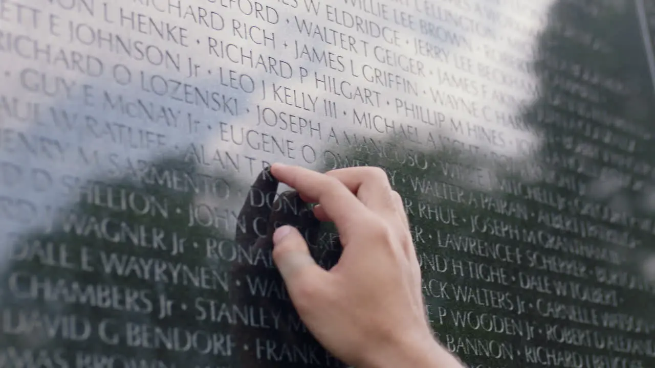 A person rubs their hands on a military personnel tribute