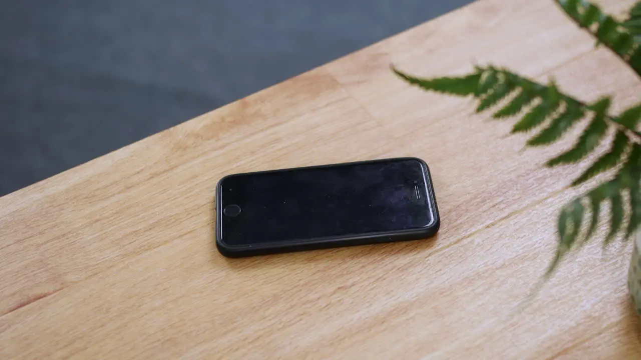 A smartphone cell phone ringing and picked up from a desk to be answered