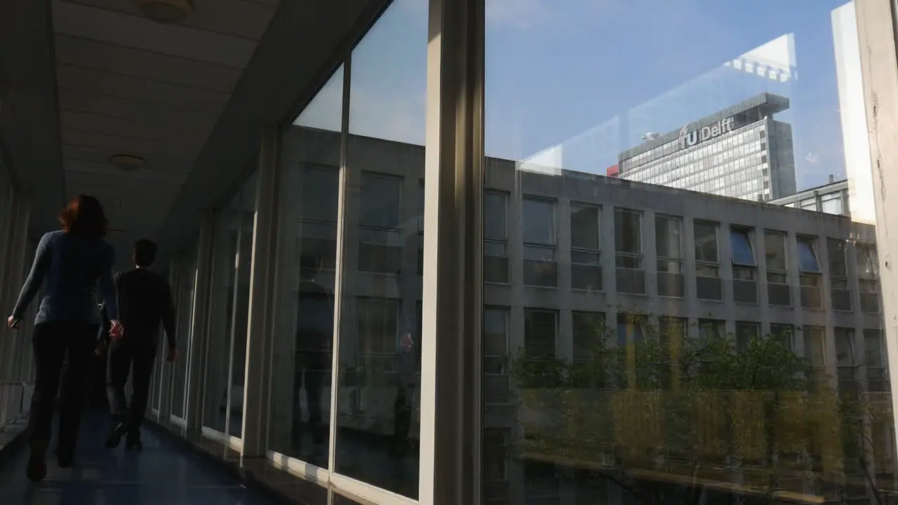 A shot of the TU Delft logo taken from a building in the university campus people probably scientists walkin past