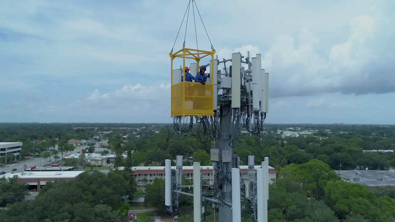 4K Aerial video of telecommunications tower being serviced by technicians