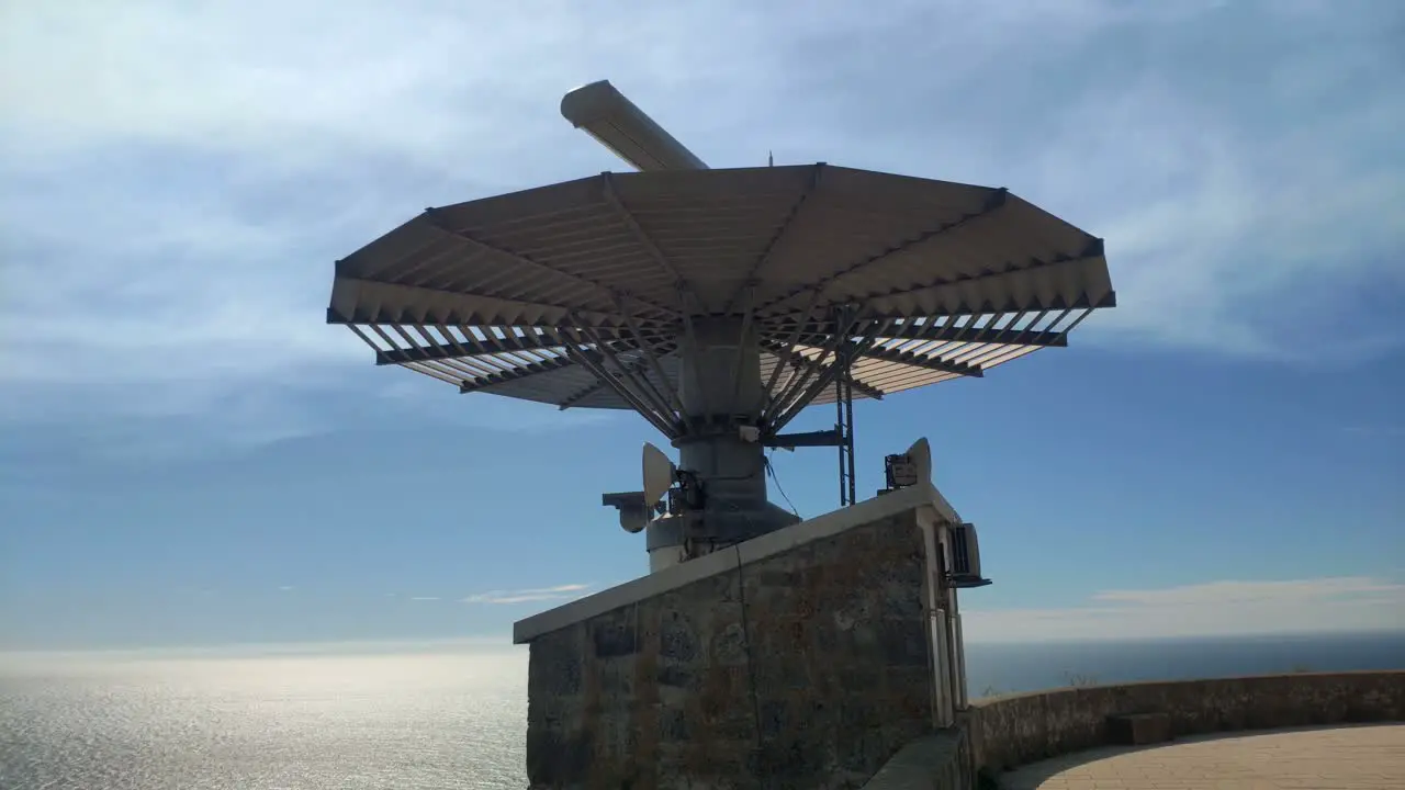 Radar for maritime traffic control at the top of the mountain with the reflective sea in the background on a sunny summer day shot blocked from below