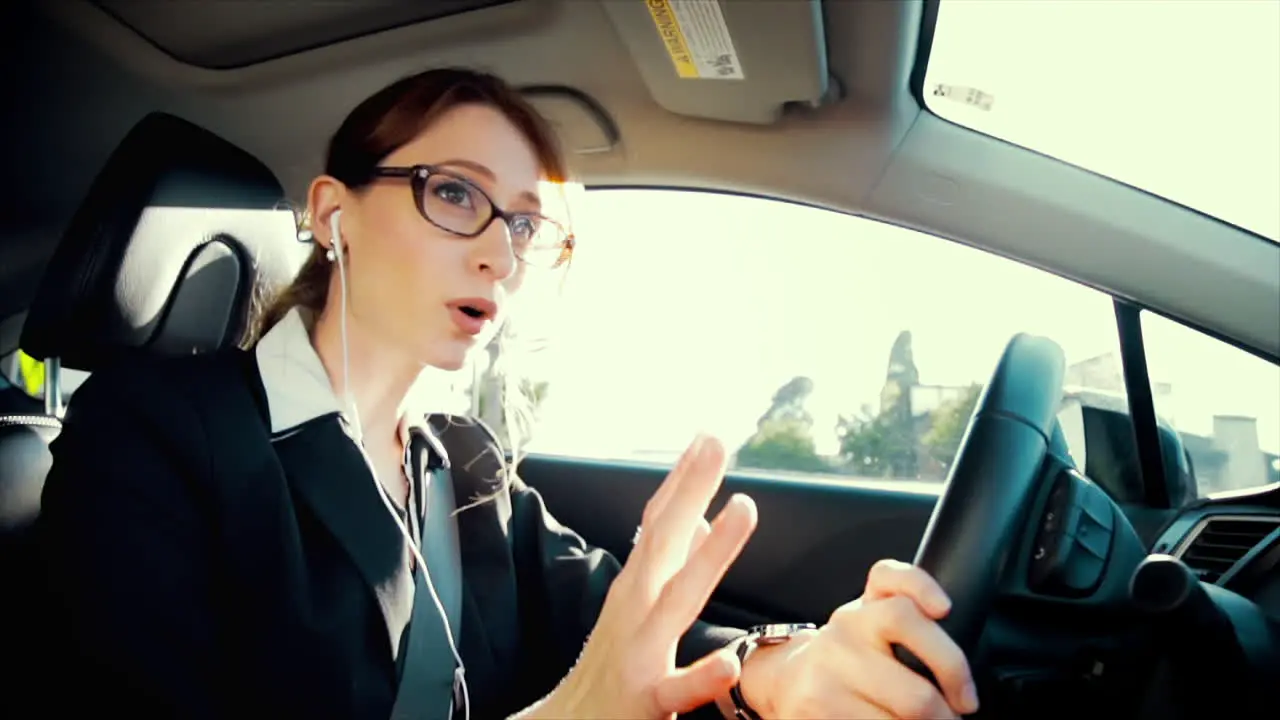 Attractive caucasian business woman driving while talking on the phone through her headphones