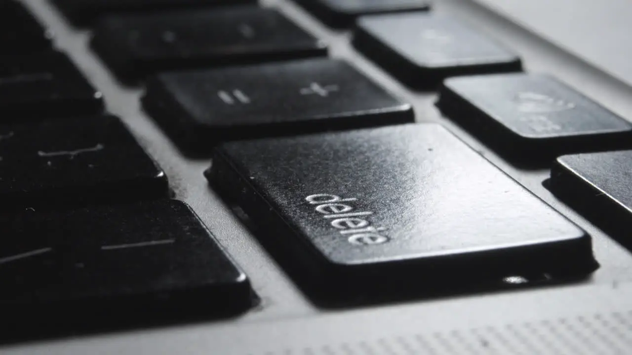 Close-up of Finger Pressing "Delete" Key on Laptop Keyboard