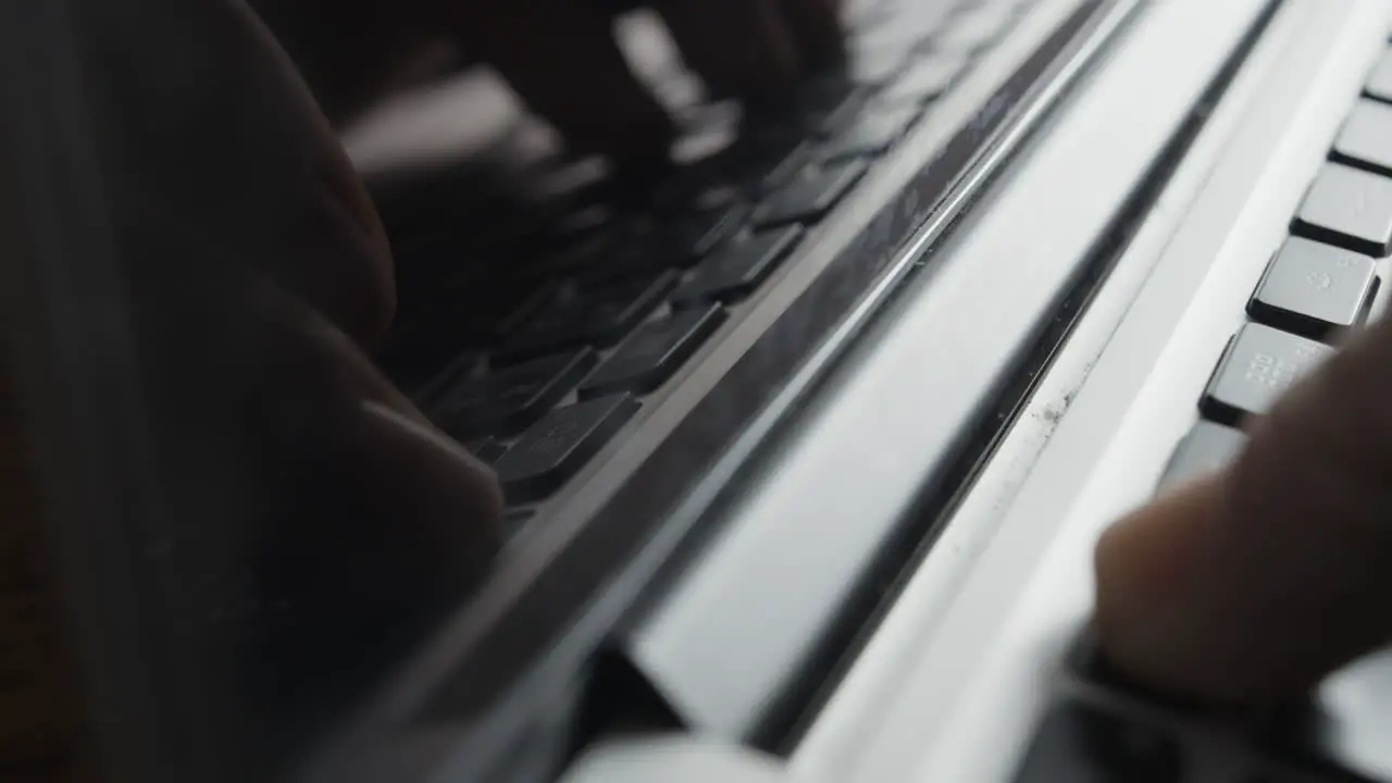 Laptop Screen Reflecting Image of Fingers Typing on Keyboard