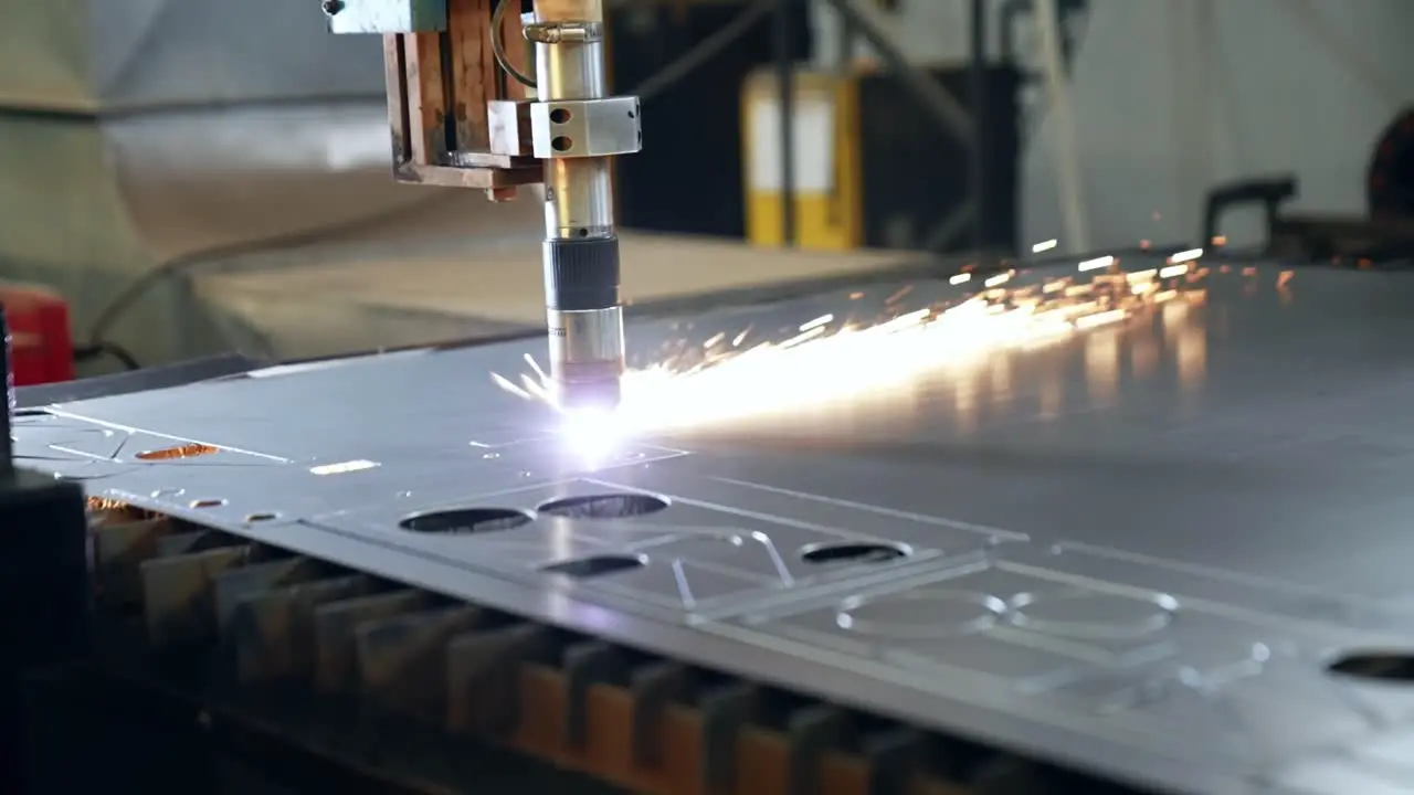 industrial laser cutter cutting figures in a sheet of steel while sparks fly in slow motion