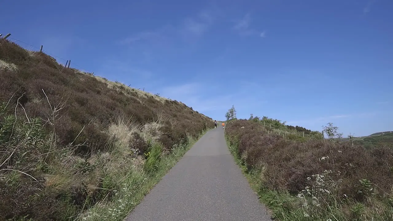 Two people walking slowly up a country road path