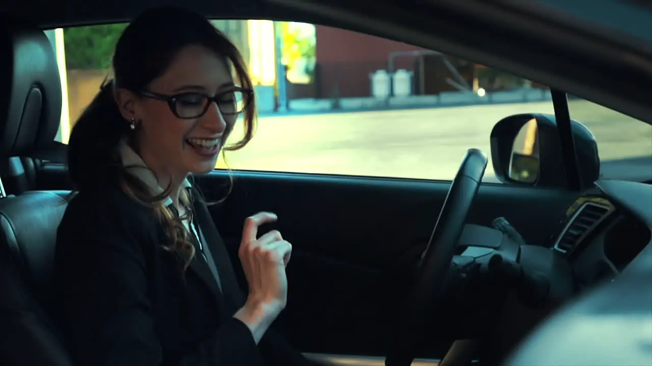 Attractive caucasian business woman in a parked car while talking on the phone she smiles and laughs during her conversation