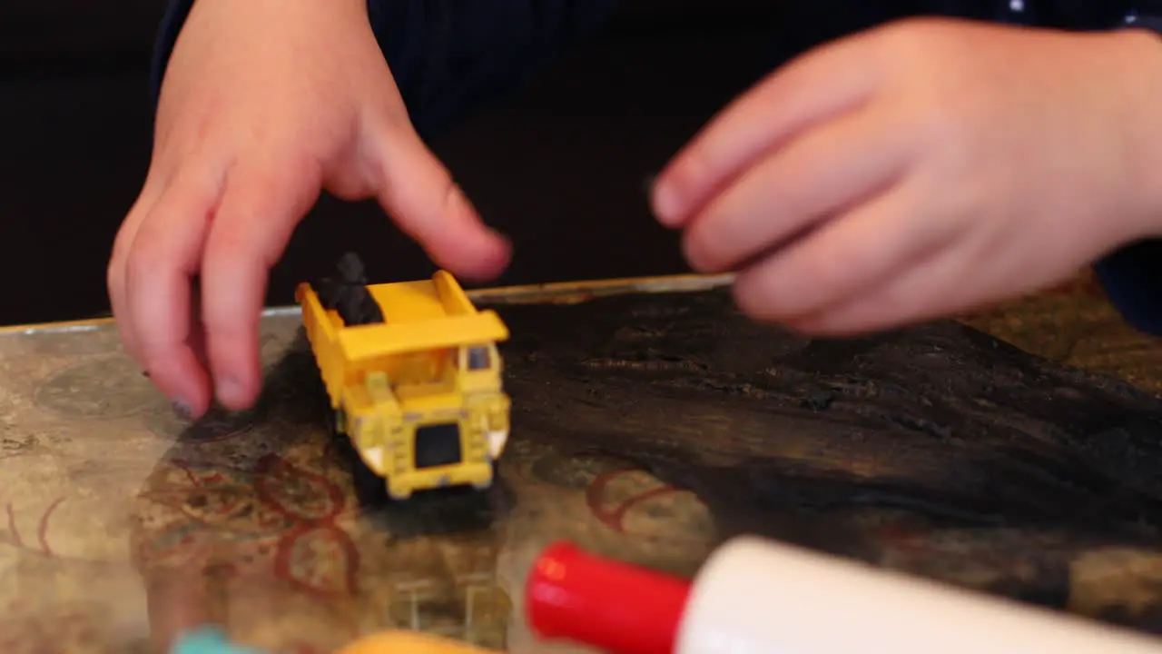 A close-up of a child's hands playing with his tow digger and clay inside during lockdown