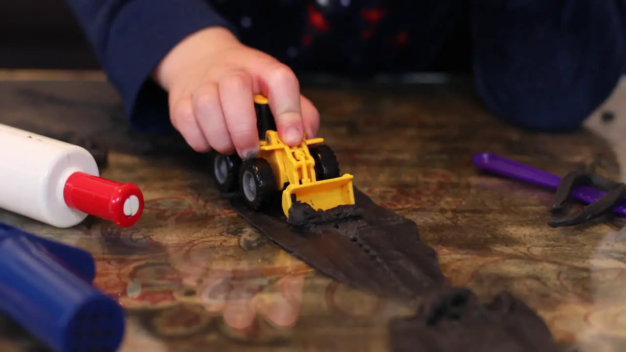 A boy playing with his tow digger and clay inside during lockdown