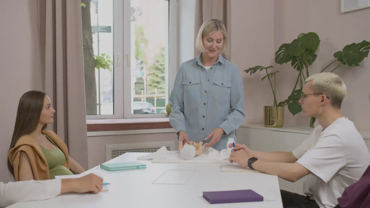 Blonde teacher talking in class with toy baby