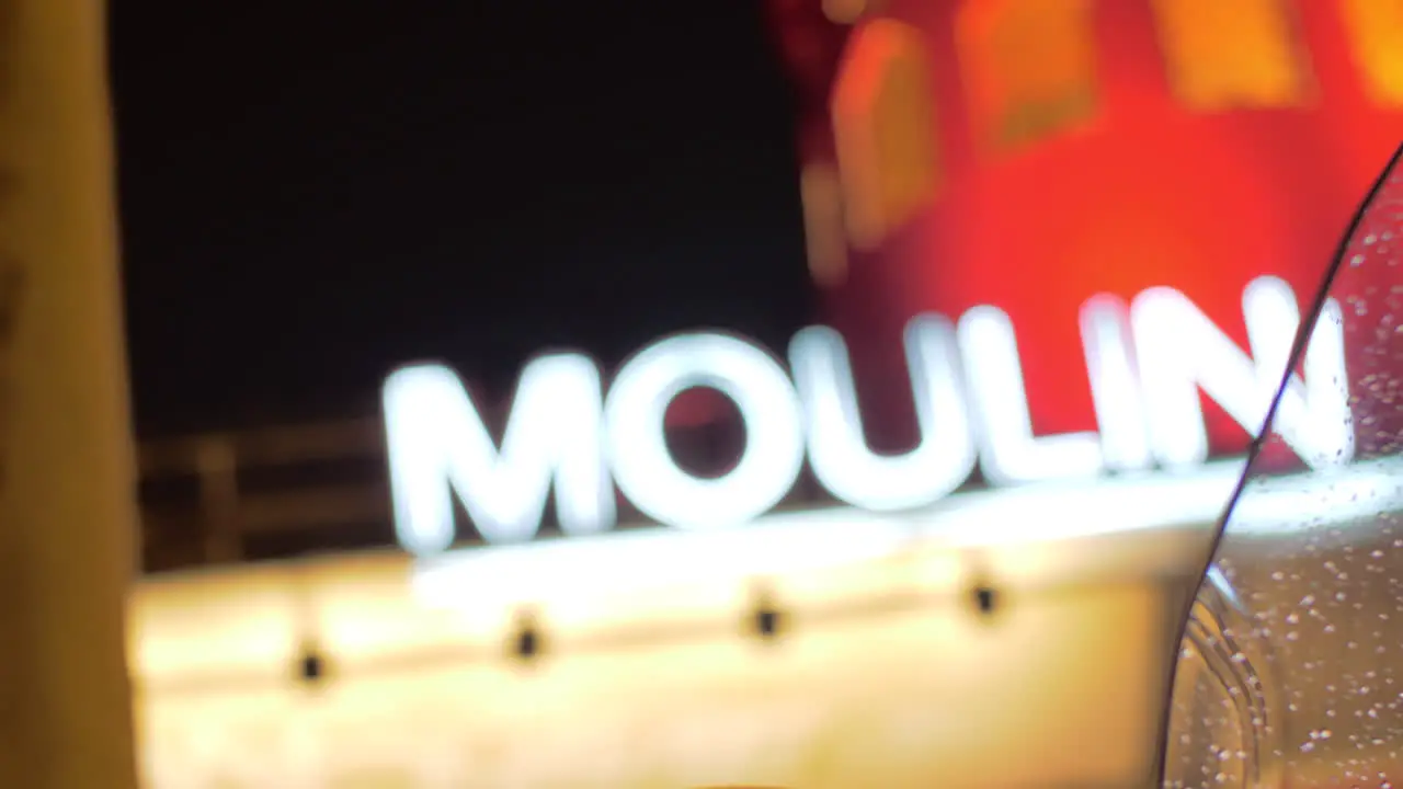 Moulin Rouge view through wet motorbike windscreen at night Paris