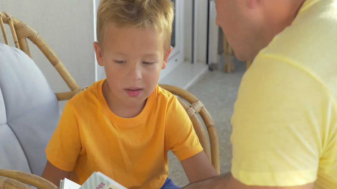 Child and father reading book on the balcony