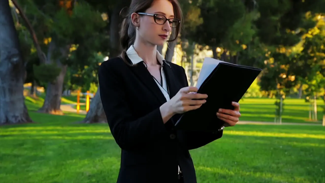 Attractive caucasian business woman flips through paperwork in her folder takes a look at a document and then exits