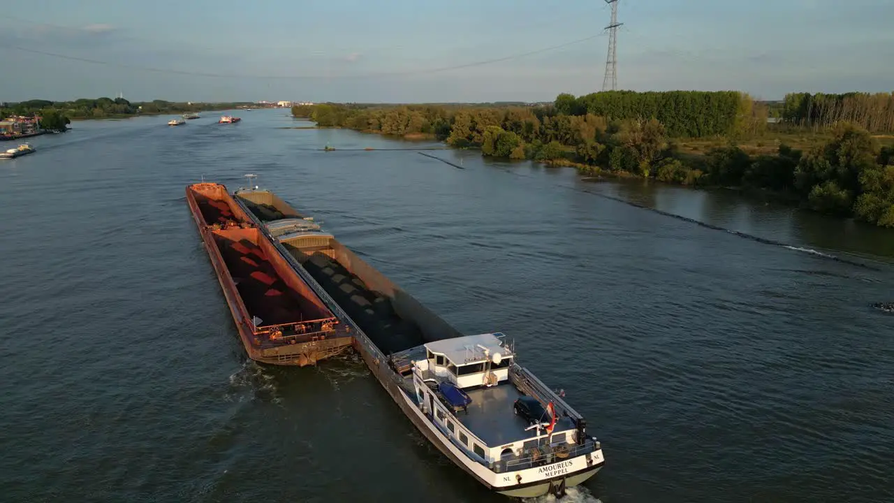 Aerial view of cargo ship with bulk material in barges slowly moving on river