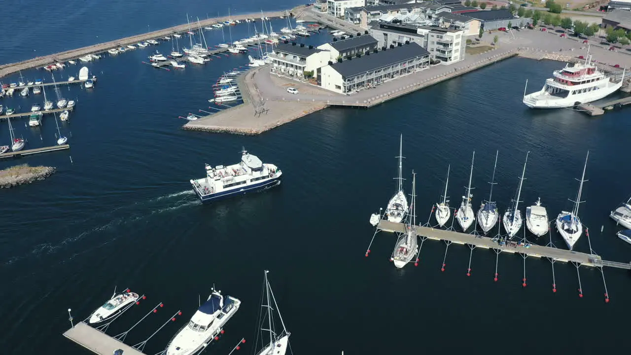 Aerial drone view of a small Scandinavian city port with a passenger vessel transport ship boat entering the harbor at the end of a trip for tourist travelling across Swedish sea ocean on calm waters