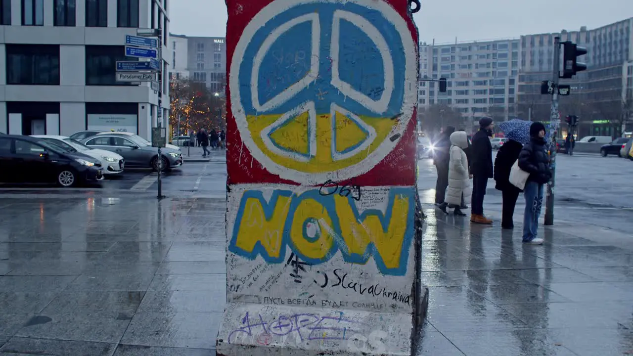 Part of the Berlin Wall in Potsdamer Platz square on a rainy day with tourists