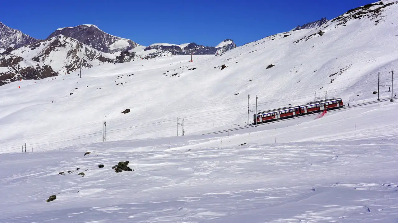 Gornergrat mountain railway moving through the ski pistes of a ski resort near Zermatt in the snow covered mountains of the Swiss alps Switzerland