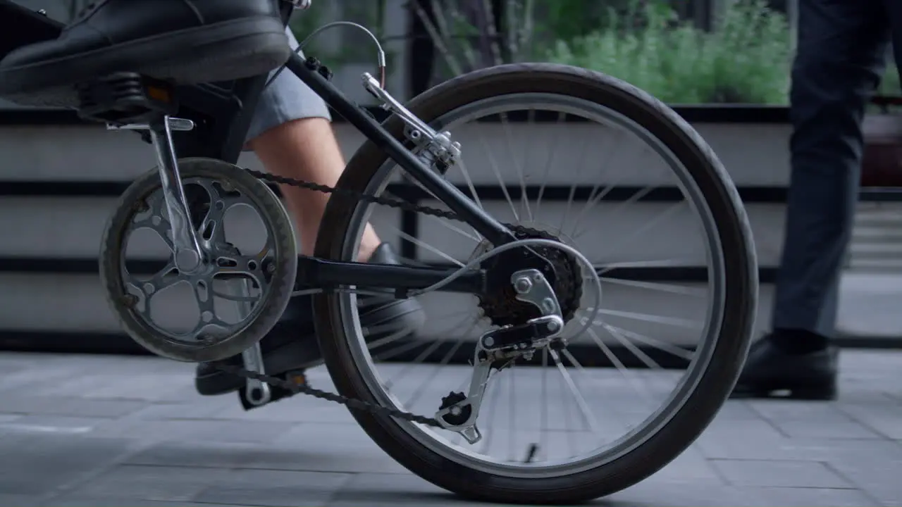 Male legs riding bicycle in black shoes at downtown close up Rear wheel view