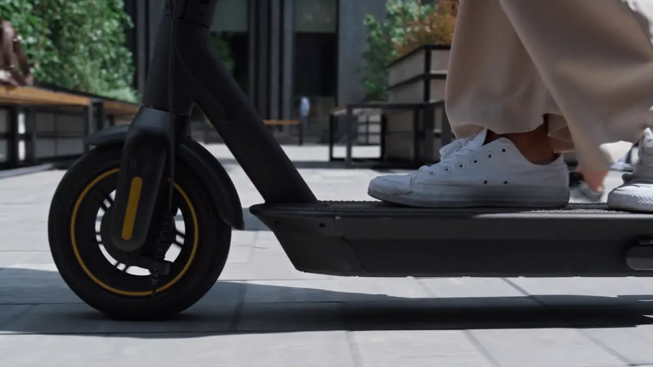 Closeup female legs riding kickscooter in white sneakers Urban traveler concept