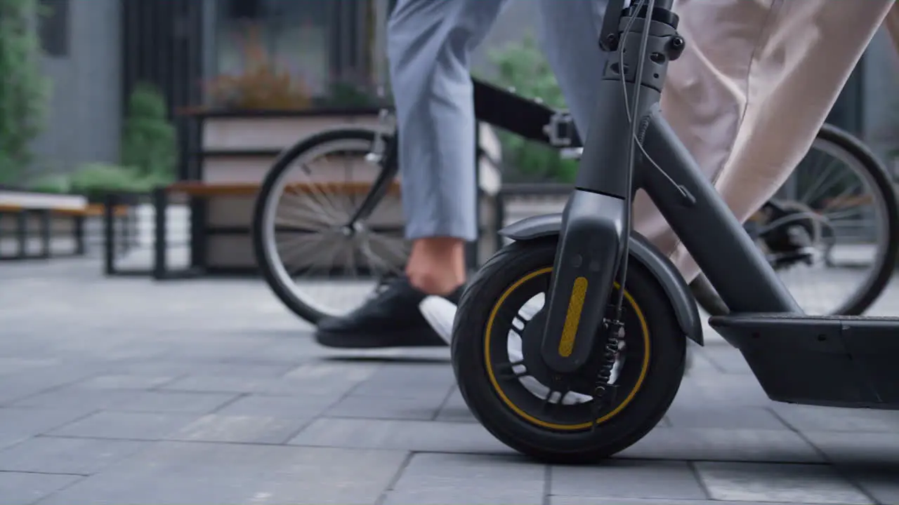 Managers legs walking downtown street Front bicycle scooter wheels close up