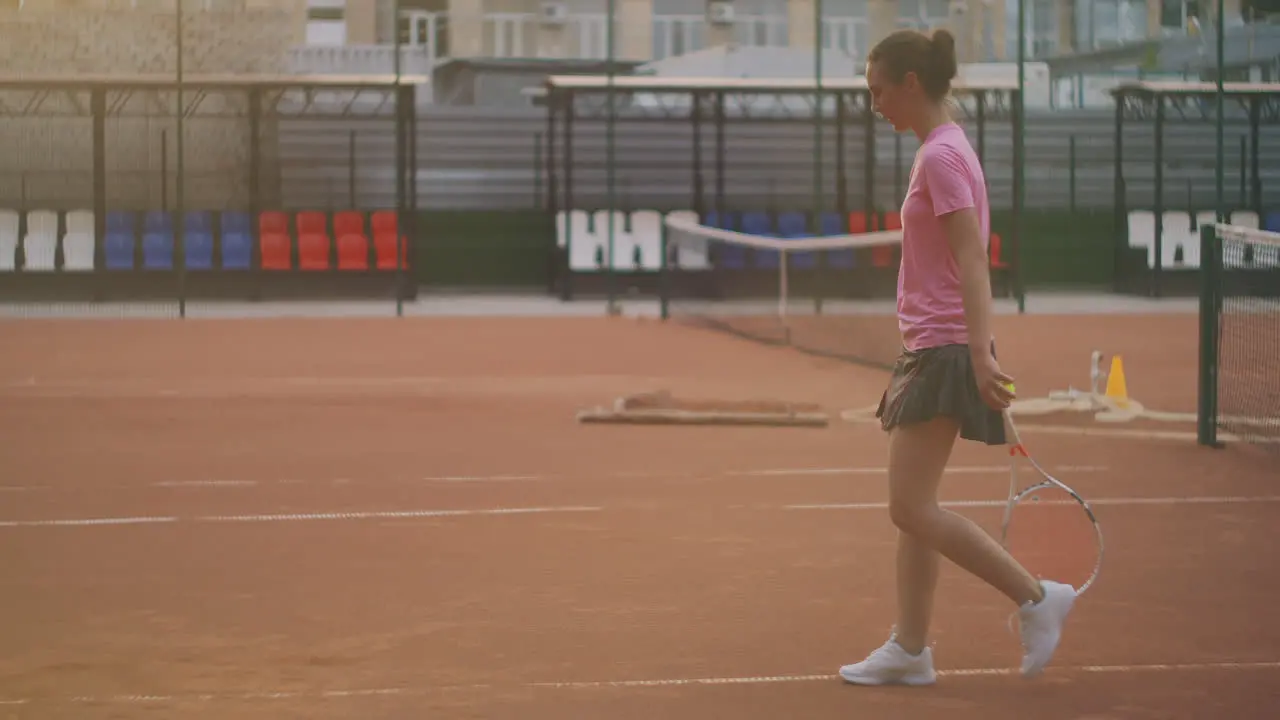 A woman walks on a tennis court with a racket and knocks the ball on the ground concentration will to win