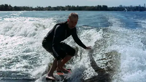 Sportive man surfing on wakeboard on waves in slow motion