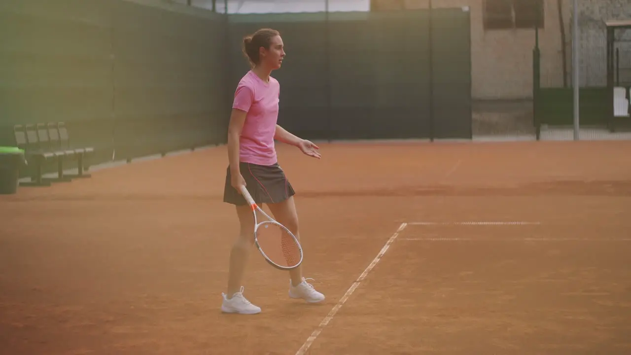 A tired brunette female tennis player walks along the tennis court recuperating and concentrating Break in a tennis match Tennis player after the match on the map at sunset in slow motion