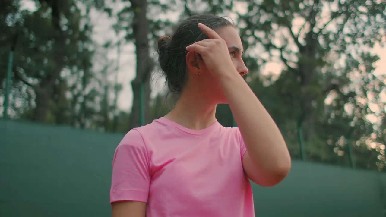 A girl in a pink T-shirt with a tennis racket in the ready position