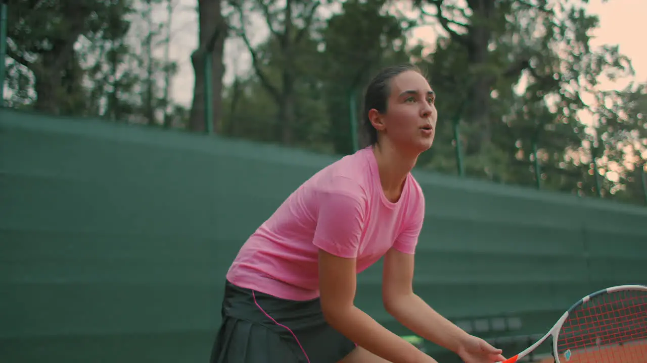 Young tennis player backhand Young girl in pink t-shirt playing lawn tennis at sunset Eye Level